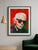 Framed 75×100 cm Karl Lagerfeld fine art print by Marcel Kozik displayed in a modern living room with minimalist decor, wooden pendant lamp, and green velvet chair.